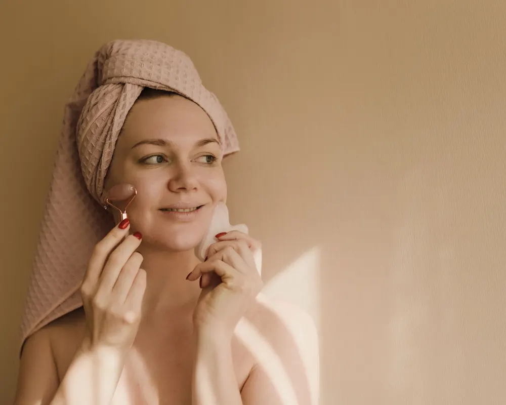 Smiling client with her hair wrapped in a towel, touching her cheek