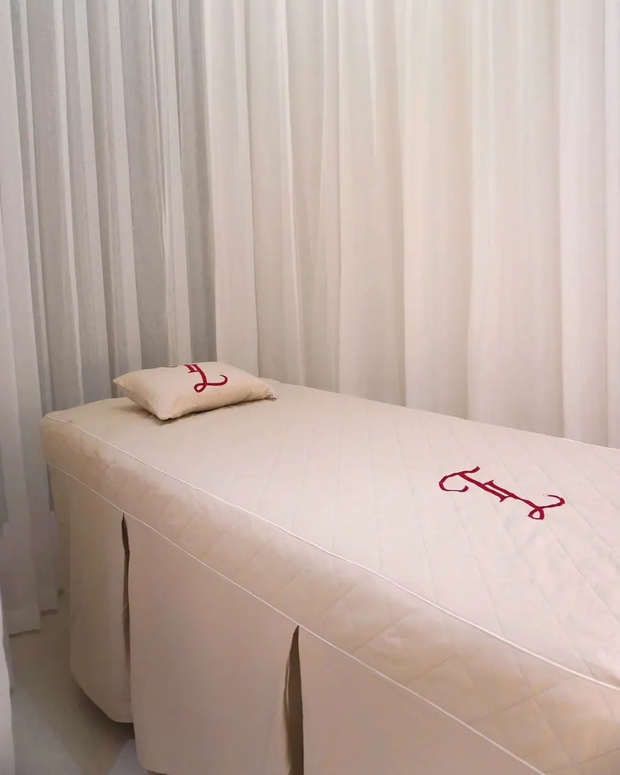 A calm treatment room with a made-up bed and soft curtains