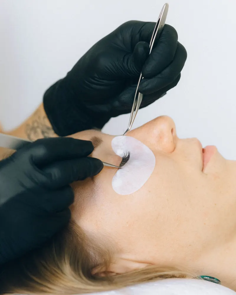 Lash artist applying lash extensions with fine tweezers