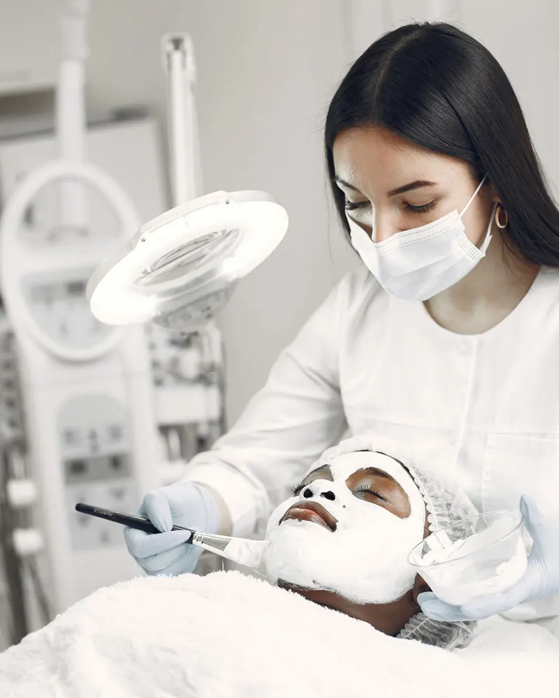 Skin therapist in a bright treatment room working with a client