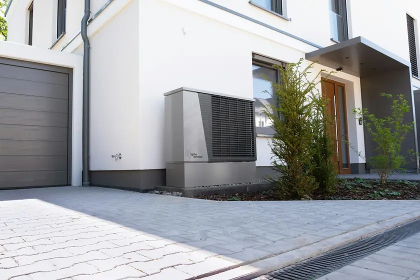 New outdoor heat pump unit beside a modern home entrance