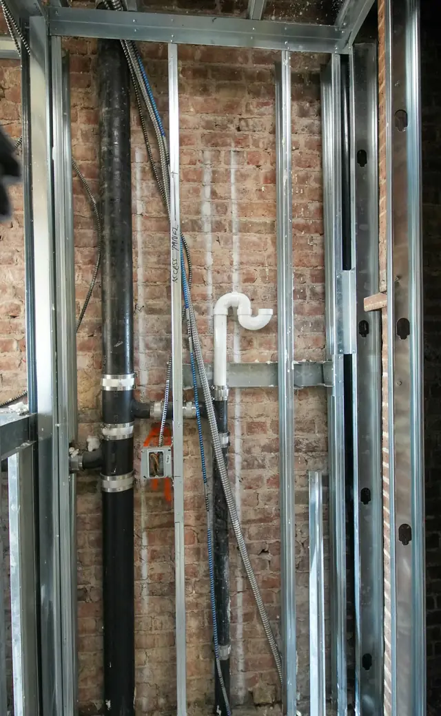 Open wall with new supply and drain lines between metal studs