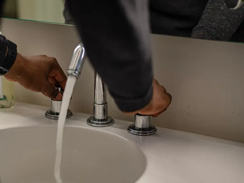 Hand adjusting a modern bathroom faucet