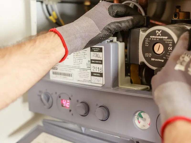 Technician servicing a boiler control panel