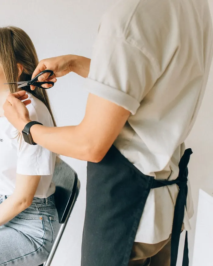 Stylist sectioning a client’s hair in a bright studio