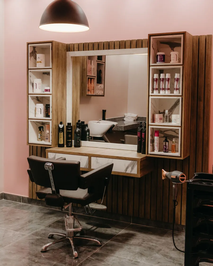 A warm, softly lit styling station with a large mirror and shelves