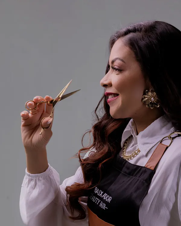 Lena Vale holding scissors and a comb, smiling