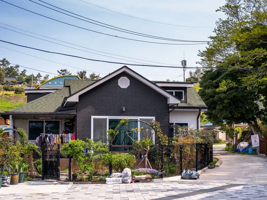 Dark-sided home with a steep gable roof and a planted front garden