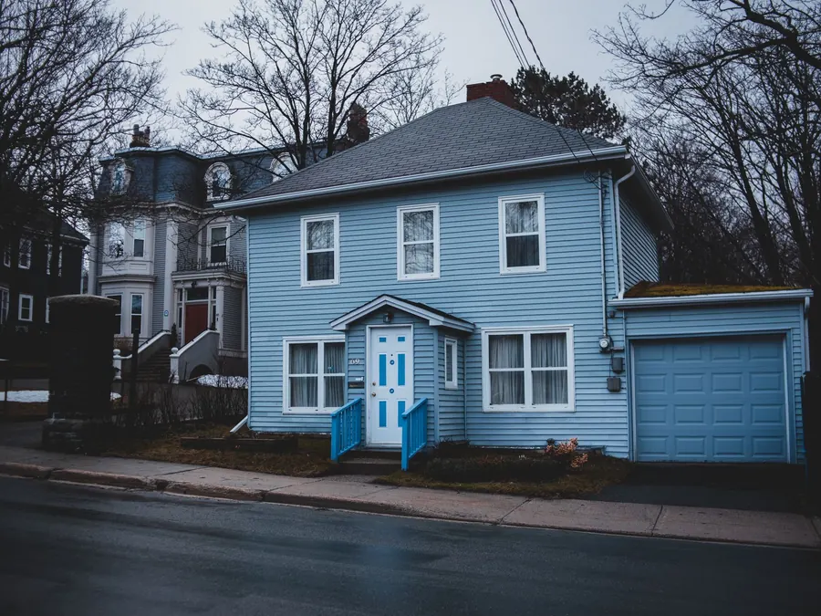 Blue two-story house with a repaired roof